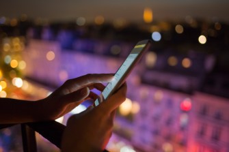 Woman using her mobile phone , city skyline night light background