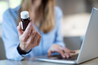Close Up Of Woman At Home Looking Up Information About Medication Online Using Laptop